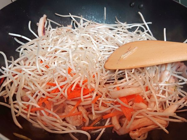 炒出醬油香味後，倒入豆芽、紅蘿蔔拌炒，炒到豆芽略扁。