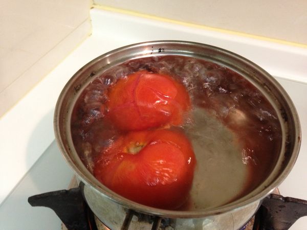 將牛番茄靠近蒂頭的地方劃一刀後丟進滾水裡，煮到表皮開始翹起就可以取出並將外皮剝掉。