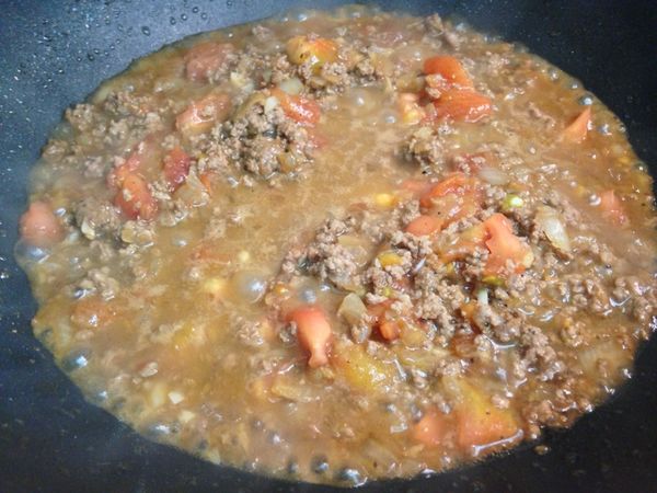 依序將蒜末、洋蔥丁炒香後，再放入牛絞肉，並加入[調味料]拌炒幾下，加入番茄塊，並加約1杯的水(量米杯)，中大火滾到肉醬變濃稠即可關火。