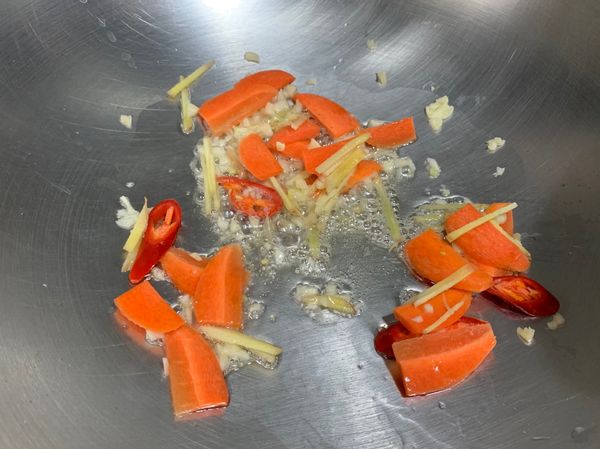 熱鍋下1大匙油，爆香蒜末、薑絲、辣椒，紅蘿蔔，接著下2大匙高湯煮滾