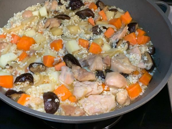 加入1米杯香菇水，再倒入1.2～1.3米杯的水，此處的水量要比平常煮飯水量少，因為調味料及食材本身均帶水分，所以不能使用1:1的比例喔！否則煮出來會很軟爛～

接著蓋上鍋蓋小火(盡量轉小點)燜煮10分鐘。