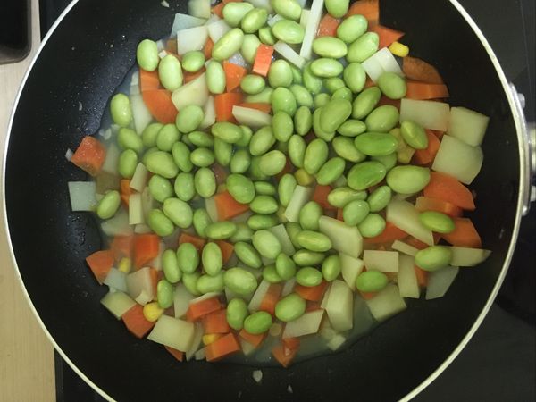 接著加入毛豆仁下去，並加一點玉米罐頭的水（或飲用水也可以），蓋上鍋蓋將食材煮熟
