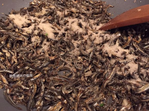砂糖加入鍋，與小魚乾一起拌炒。灑幾滴水，幫助砂糖溶化；因為砂糖溶化後，會均勻地裹在小魚乾上，口感更美味。