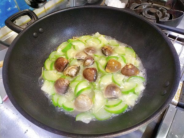 掀蓋後加入蛤蜊翻動一下，煮到蛤蜊都開了就加點米酒去腥即可。