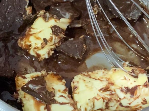 黑巧克力與無鹽奶油用最小火邊攪拌邊加熱至滑順狀，放涼後加入細砂糖拌勻，