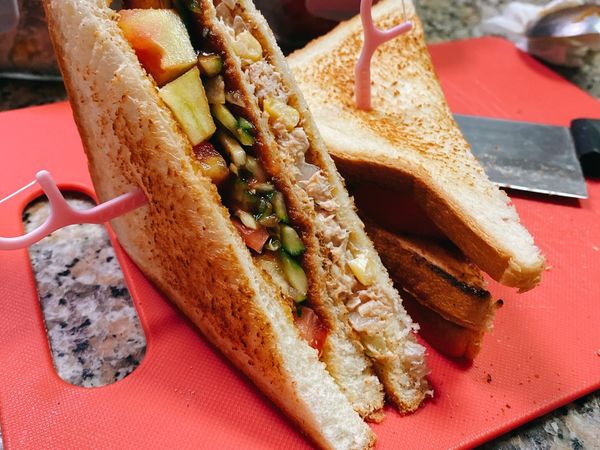 吐司三片正反烤金黃酥脆，第一片抹鮪魚玉米洋蔥沙拉，第二片放番茄片小黃瓜在加入一點番茄醬跟黑胡椒粒去生味，第三片吐司蓋上去即可。