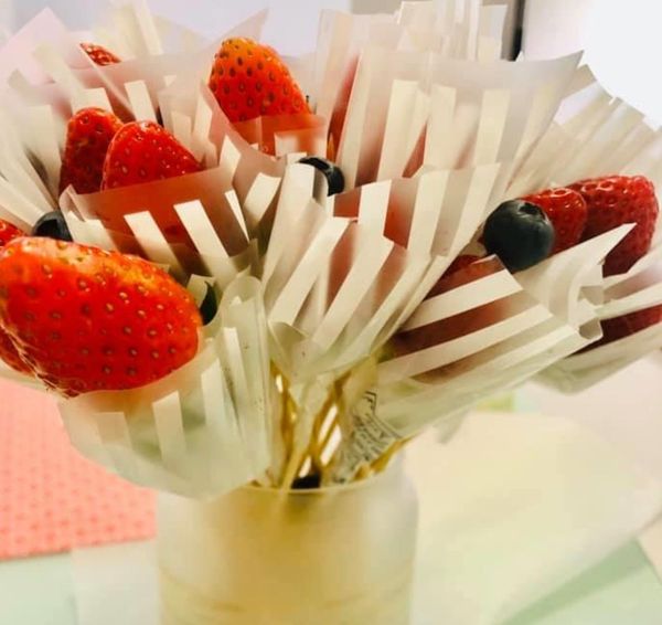 草莓用竹籤串著，每根包上半透明包裝紙，放入瓶子中。