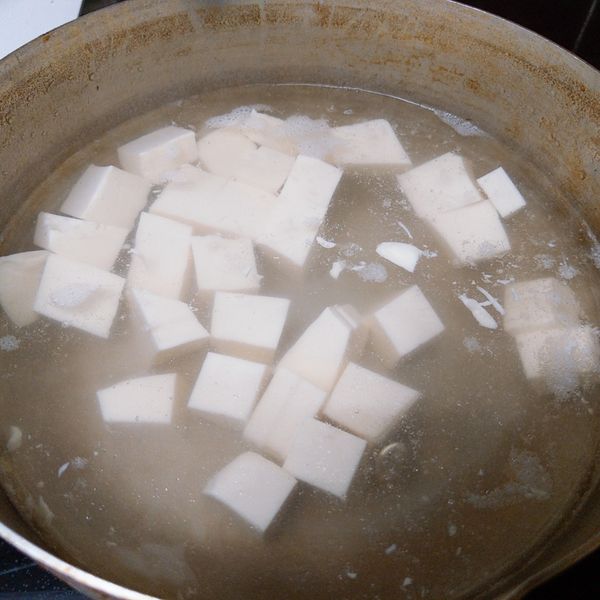把盒裝豆腐切塊放入加有鹽巴的熱水中煮5分鐘.