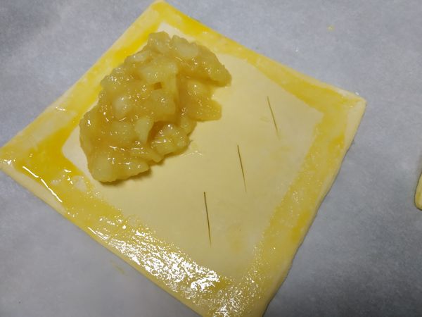酥皮室溫解凍後分左右兩邊
右半邊切三個斜刀口
左半邊放蘋果泥
外圍一圈刷上蛋黃液準備封口