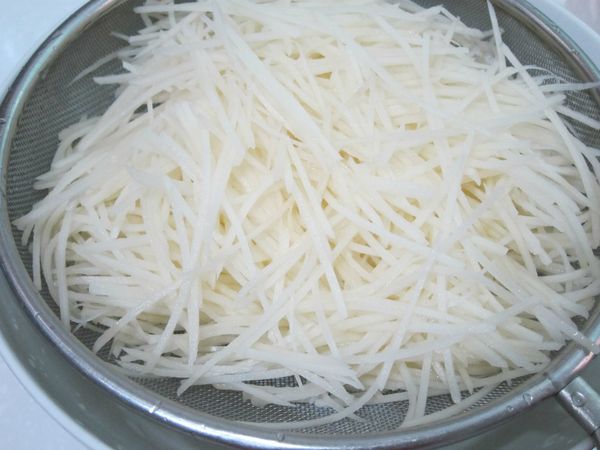 馬鈴薯去皮後以刨絲器刨成細絲，用水沖洗過，瀝乾備用。