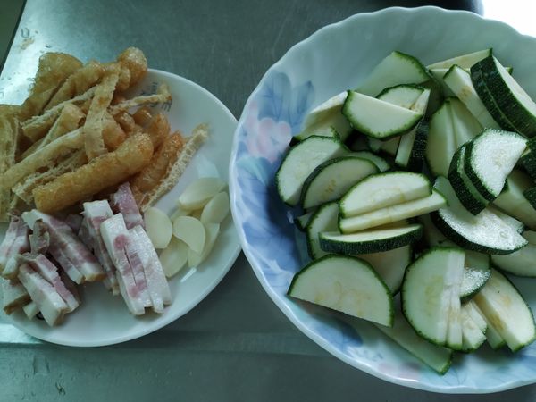 櫛瓜切圓片再對切，豆包和培根切小條狀，蒜頭切成蒜片