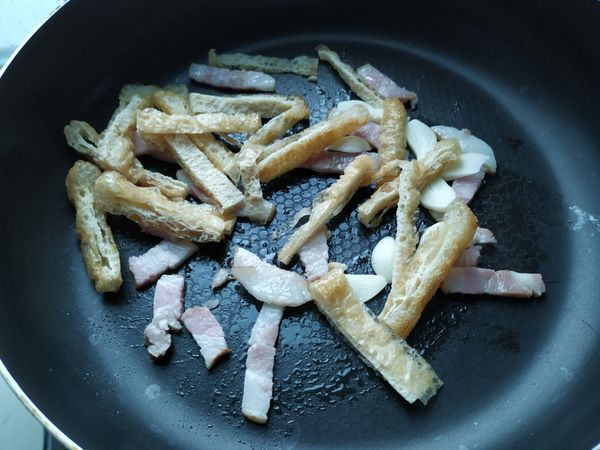 培根煸出油脂後，放入豆包和蒜片拌炒