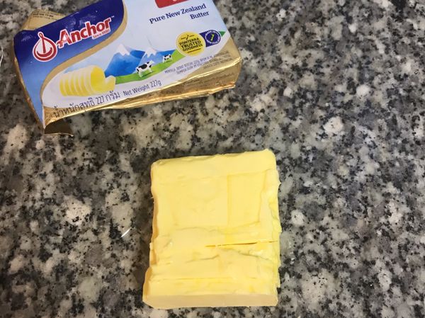 工作台上鋪ㄧ張保鮮膜；奶油秤切排成方型，