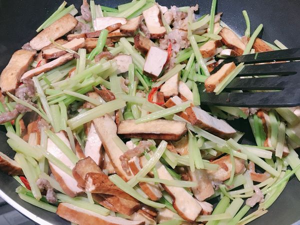 因豆乾有加一匙鹽先調味了，故芹菜可以加少許的鹽調味就夠了，另外加入白胡椒粉、香油增加香味。調完味後加入辣椒增添味道及色彩，加入後攪拌一下即可起鍋