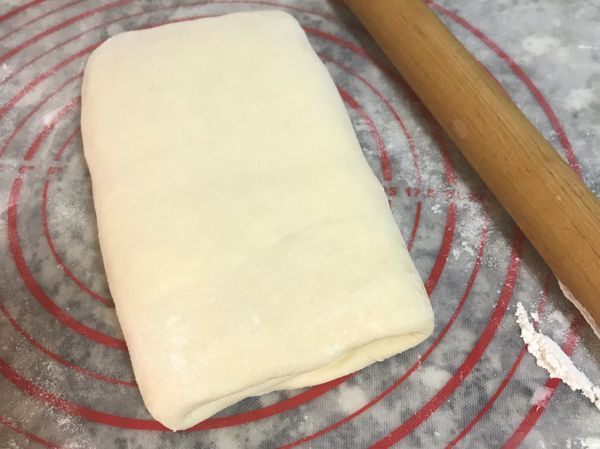 再取出，工作檯和麵皮上都撒些手粉，邊壓邊桿開後，再摺三摺；總共重覆摺4次。