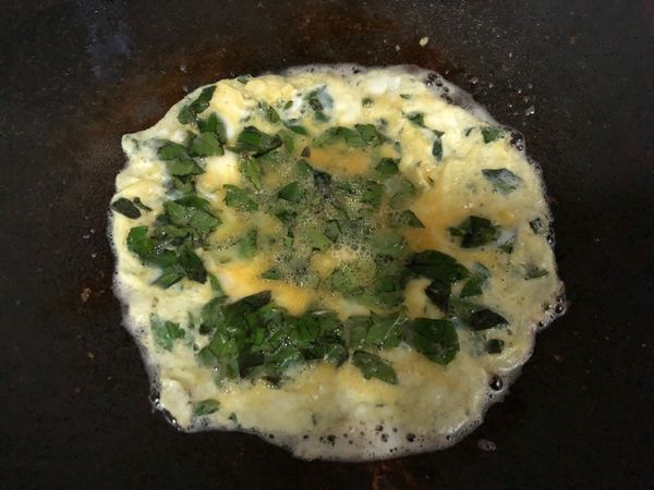 九層塔洗淨後稍微切碎，加入打散的蛋液中用鹽巴調味，倒進熱油中並旋轉鍋子，盡量把蛋液平均擴散