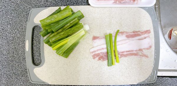 將肉片兩片交叉鋪平，三支蔥段捲起來