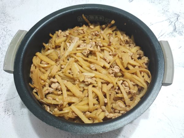 將拌炒好的竹筍料倒在洗好的米上