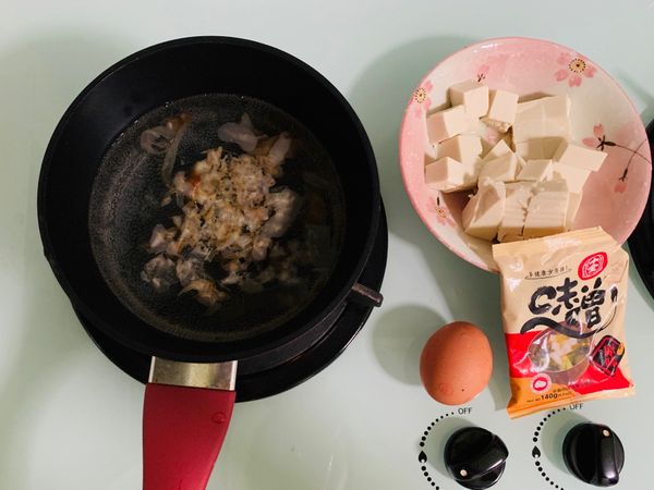 水中放入柴魚片，煮滾，同時準備其他材料（切豆腐和青蔥及打蛋）