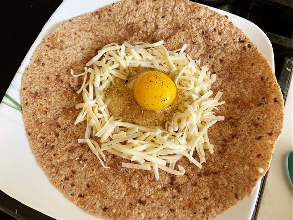 墨西哥餅上先放起司排出圓圈，把蛋打在中間，撒上一點鹽和胡椒