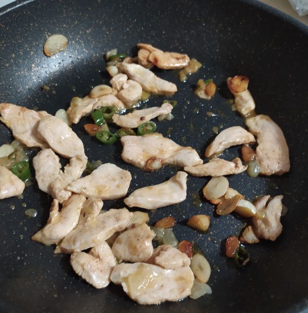 蒜有點微黃後，下鷄肉片、醃檸檬和辣椒，中大火，肉片要把他攤平，等肉都變白熟透且有些微焦黃後，加一小匙白酒之後熄火。（這步不能煎久，否則鷄胸會老）