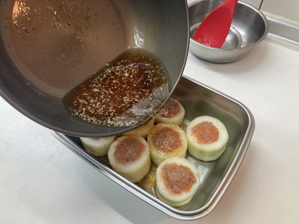 將醬汁倒入裝有黃瓜鑲肉的不鏽鋼盒中