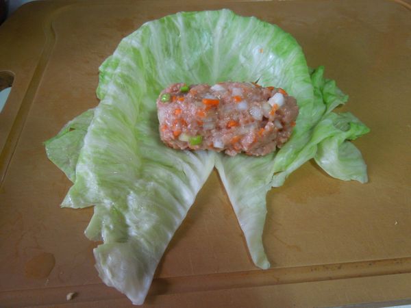 將餡料均分成四份，取一份塑型呈圓柱形，放置在高麗菜葉上。