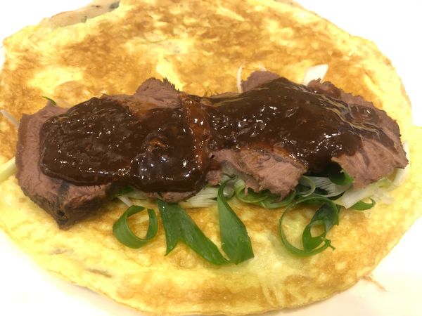 把泡冰水的蔥絲甩乾，放在蛋餅上，放上牛腱薄片，刷上醬汁後再卷成肥肥的蛋捲！
(肉要放在蛋餅邊邊上才比較容易捲）