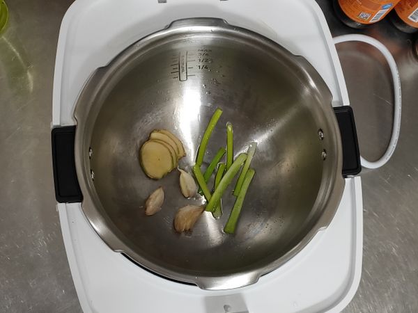 萬用鍋選擇“煎烤爆炒”模式，時間設定2分鐘，熱鍋完成後放入一大匙油，依序放入蔥、薑、蒜爆香