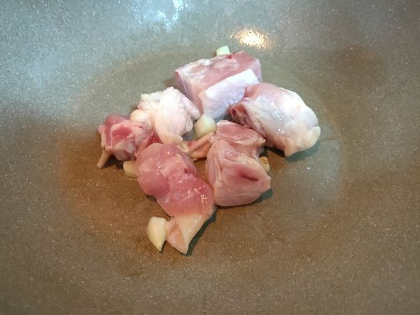 下油炒香蒜末，爆香之後下雞腿肉一起拌炒。