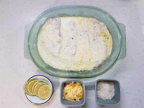 烤6分鐘後，取出烤盤。

準備檸檬片、比薩起司、麵包粉等烤魚配料。