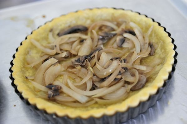 準備一只烤至半熟的放涼派皮，先舖上洋蔥、洋菇當底。