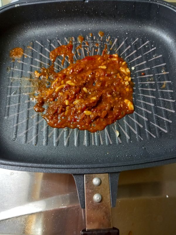 利用鍋中剩餘的油來炒豆瓣醬，先下一部分蒜末爆香，放入半碗豆瓣醬炒出香氣