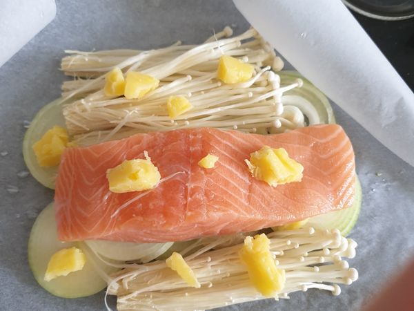 將洋蔥墊於底層，放上金針菇與鮭魚，放上奶油。
用烘培紙包起來，盡量包緊。
