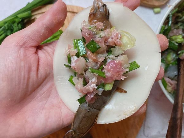 拿一張水餃皮，輕輕拉一下，先放上全蝦，再放上內餡，水餃皮四周沾水