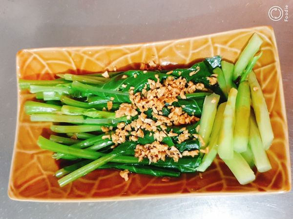 燙好的芥藍擺盤，淋上醬汁、蒜油，撒上蒜酥