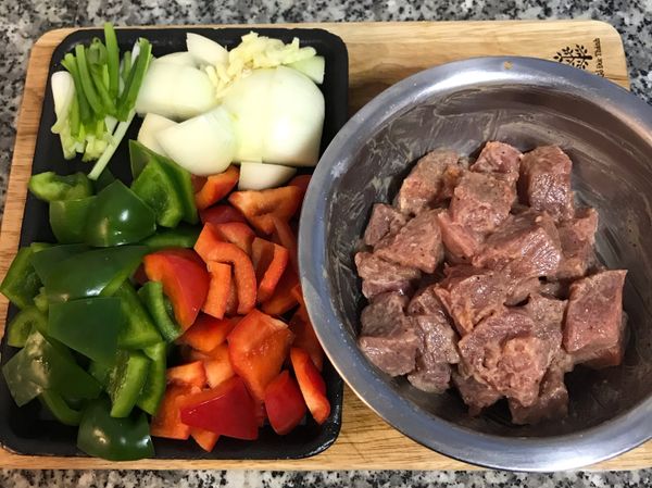 牛肉切成小方塊用醃料抓勻；洋蔥切塊；青椒、紅甜椒洗淨去梗去籽，並除去裡面白色的部位後切塊；蒜頭拍扁去皮切片；蔥洗淨切段；