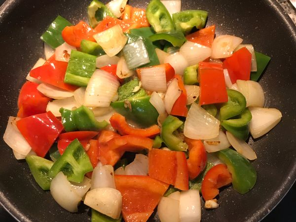 下青椒與紅椒大火快炒，放入鹽與黑胡椒粉調味，再放少許水，嗆出鑊氣；