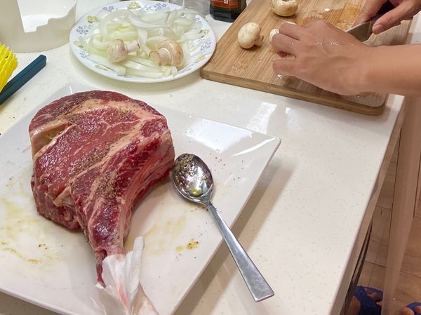 戰斧牛排一支，拆封後修掉邊緣多餘油脂筋膜，留下備用。
肉雙面抹少許油，灑上蒜味胡椒

配菜洗淨切段，今天剛好冰箱有什麼煮什麼～
可選擇自己喜好的蔬菜配色即可。
（謎之音：當天洗菜小幫手說個人愛吃洋菇，默默的加量🤣 大推👍）