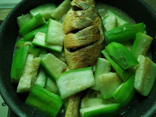 再拌炒均勻一下，然後將絲瓜撥到鍋子兩邊，中間放入煎好的黃魚，蓋上鍋蓋