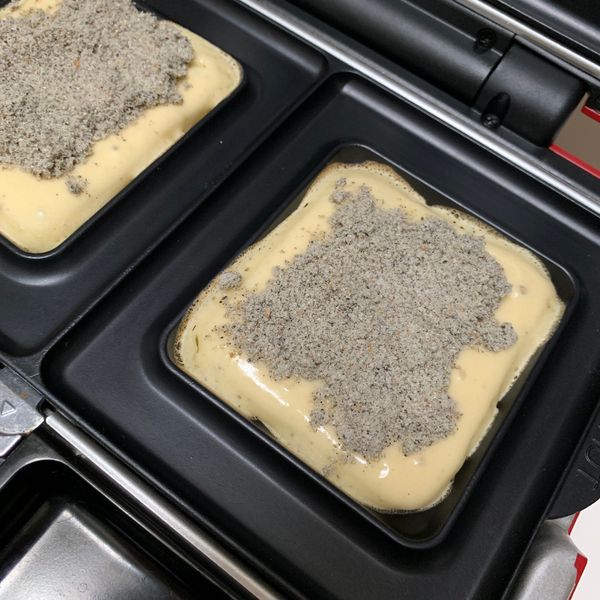 待麵糊微起泡後，加入芝麻粉(花生粉)後，在其上頭再覆蓋些許麵糊，蓋起鬆餅機上蓋，烘烤4分鐘。