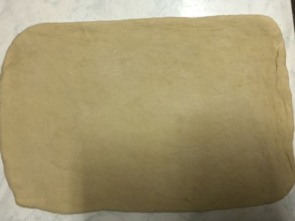 直接將麵糰取出。揉檯上撒少許麵粉。將麵糰桿成長方形。