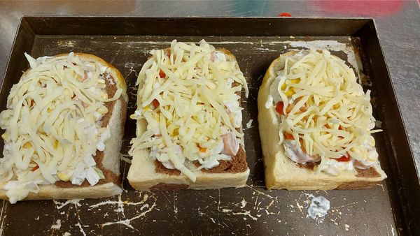 匹薩吐司，德式香腸切小塊，玉米粒，洋蔥碎，加沙拉醬拌勻，舖放吐司上，義式香料，黑胡椒粒，蕃茄醬，黃芥末醬，起司絲，進烤箱，230/130烤15～20分鐘