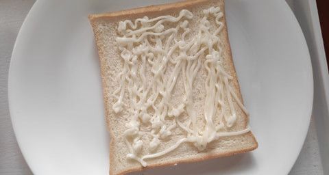 取一片薄土司，擠上沙拉醬。