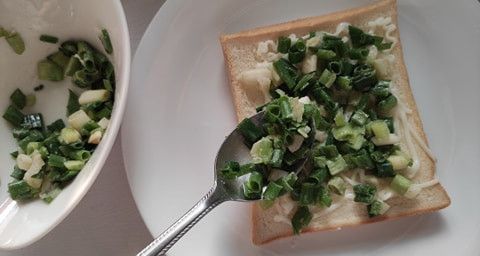 將拌好調味料的青蔥花舖在土司上。