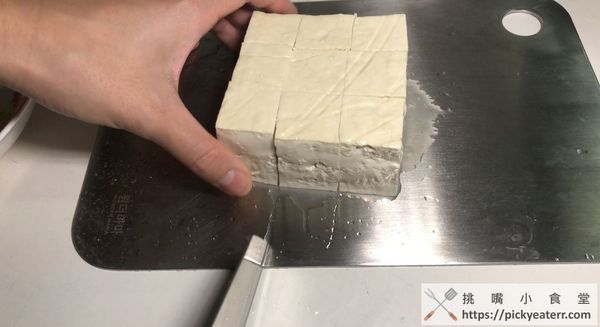 取出板豆腐並切成9塊，將板豆腐沾上蛋液後均勻地裹上地瓜粉。