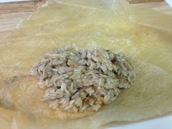 2大張腐皮裁成4份，取適量的糯米飯放入後包起成長條狀並用棉繩固定。