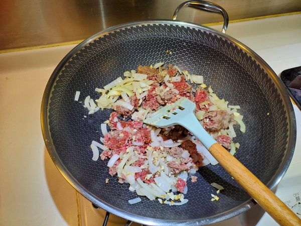 將洋蔥蒜頭爆香， 然後加免治牛肉一起炒至半熟， 如喜歡可在這裏落少許白酒。