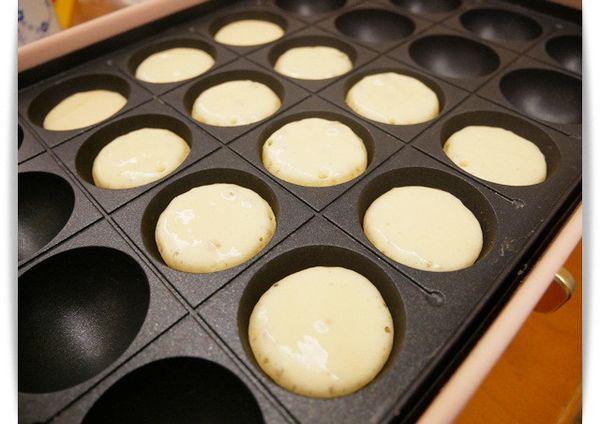 拿出章魚燒烤盤來製作，先預熱後倒入八分滿麵糊以中火加熱。