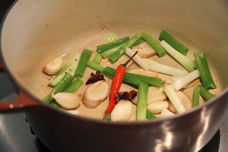 鐵鍋倒少許油放入蔥段、薑片、蒜頭爆香，放入八角與辣椒炒香